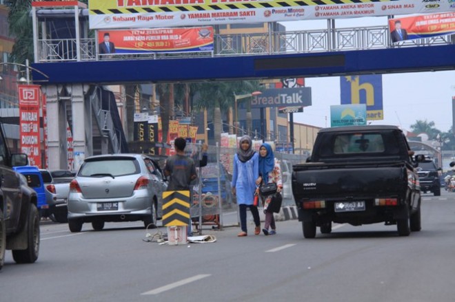 Pekerja terlihat masih melakukan pemasangan pagar pembatas jalan di depan WTC Jambi, kemarin. Sedangkan di atasnya, JPO sudah mulai dilalui warga   